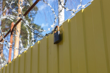 barbed wire on top of fence, lock hanging on wire, forbidden zone, stop
