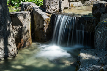 Fototapeta na wymiar small man made waterfall with long exposure inside park