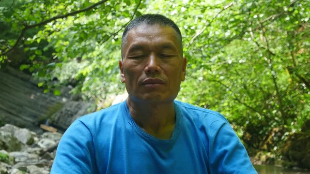 Asian man meditating in a beautiful forest