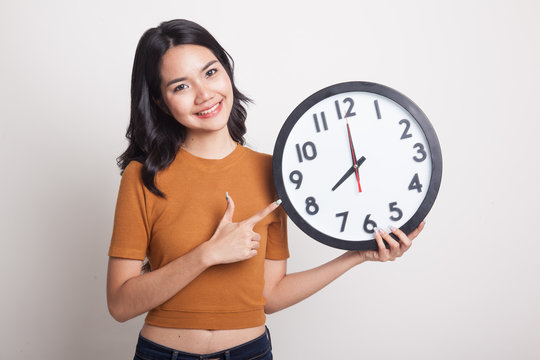Young Asian woman point to a clock.