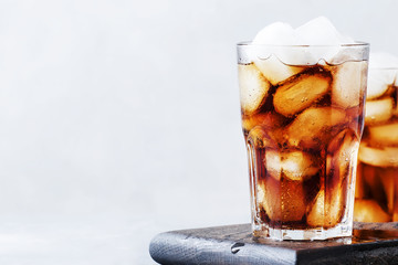 Alcoholic cocktail of rum-cola with ice, gray background, selective focus