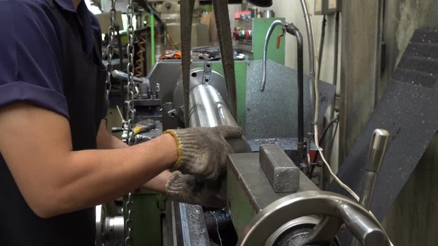 The lathe machine operator move the metal pipe from the machine. Machine operator in the factory.