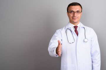 Man doctor wearing eyeglasses against gray background