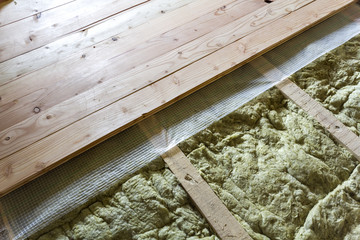 Installation of new floor of wooden natural planks and mineral wool insulation for isolation and keeping warmth. Construction, renovation, warm comfortable house concept. - obrazy, fototapety, plakaty