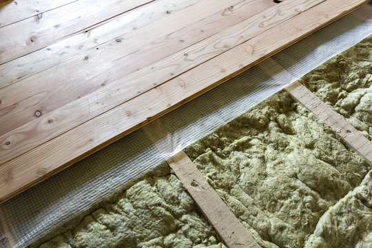 Installation of new floor of wooden natural planks and mineral wool insulation for isolation and keeping warmth. Construction, renovation, warm comfortable house concept.