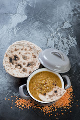 Red lentil indian masoor dal soup with chapati flatbread, high angle view on a grey concrete background, copy space