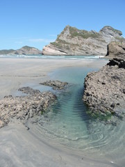 Clear turquoise water and rock formations on a beach, New Zealand