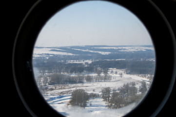 Fototapeta premium вид на заснеженную природу через круглое окно илюминатора