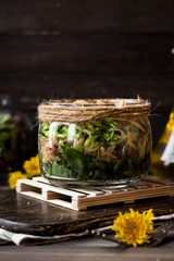 Salad from sprouts of sprouted soy and dandelion leaves in a jar
