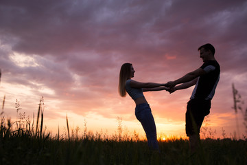 Silhouette of a young couple on sunset sky