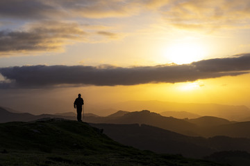 Man celebrating success on top of a mountain in sunrise.