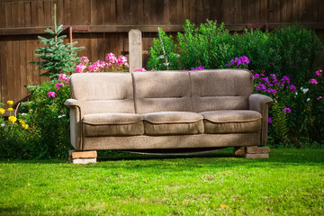 old broken brown sofa set in the garden on the bricks