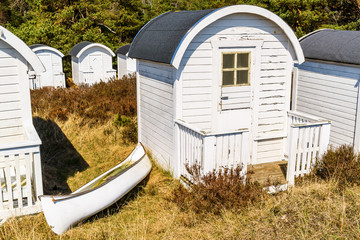 Ljunghusen, Sweden - White waterfilled canoe outside a white bathing hut.