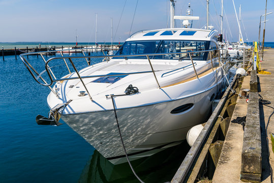Luxurious motorboat tied to a pier in a marina. Boat seen from the front. Logos and id removed.