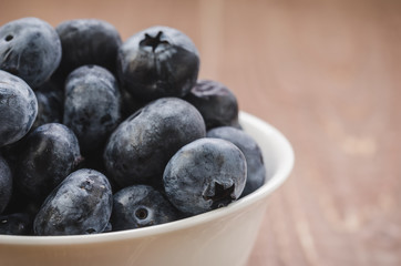 fresh blueberry in a white bowl/fresh blueberry in a white bowl on a wooden background. Close up