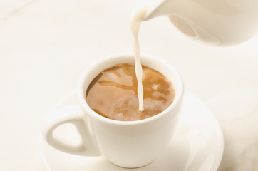 milk is added to coffee cup/milk is added to coffee cup on a white background. Selective focus