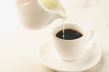 milk is added to coffee white cup/milk is added to coffee cup on a white background. Selective focus
