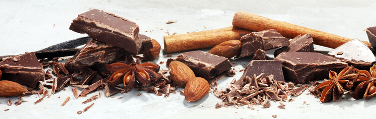 dark chocolate bars  with anise and nutson stone table and broken pieces of cocoa