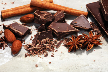 dark chocolate bars  with anise and nutson stone table and broken pieces of cocoa