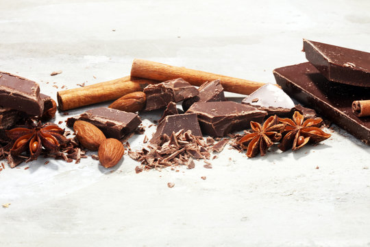 dark chocolate bars  with anise and nutson stone table and broken pieces of cocoa