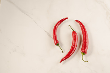 shining red hot pepper on a marble background/red hot pepper on a white marble background. Top view and copyspace