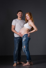 Husband and pregnant wife on gray background