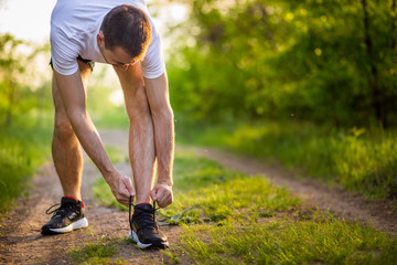 Man tying running shoes. Healthy lifestyle. Athlete tying laces for jogging on road in barefoot running shoes. Runner getting ready for training