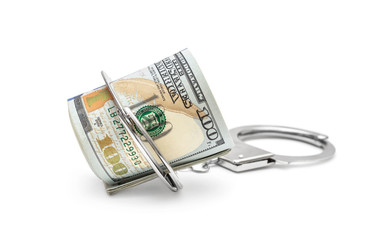 Rolled up dollar bills with handcuffs on white.
