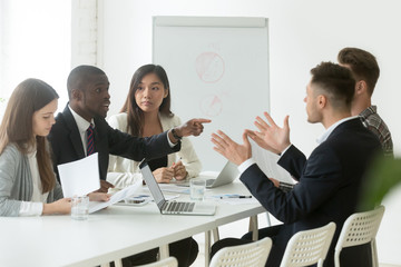 Diverse employees arguing during team meeting, african office worker disagreeing with caucasian...