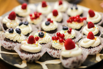 Different dessert tartlets with cream and fresh blueberry and raspberry. Selective focus. candy bar concept