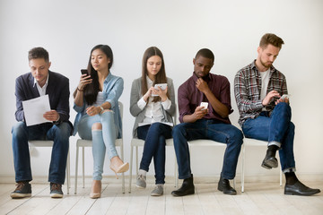 Diverse millennial unemployed people waiting in queue preparing for job interview, multi-ethnic...