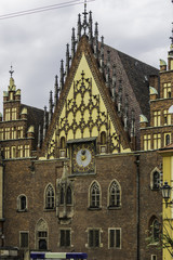 Fototapeta na wymiar Facades, roofs , sculptures,stone decoration and towers of the medieval Town Hall. Mixed style of architecture - Gothic and Baroque. Vroslav, Poland.