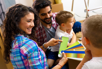 Happy young family moving into their new home. They sitting on the floor and choosing colors for the walls.