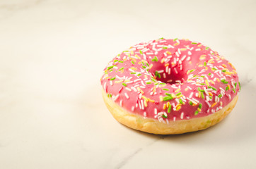 Sweet and colourful pink doughnut/Sweet and colourful pink doughnut on a marble background. Selective focus and copyspace