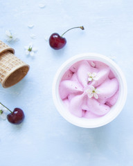 Cherry ice cream in plastic jar on blue background.