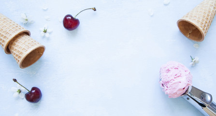 Obraz na płótnie Canvas Ice cream scoop, sugar cones, fresh cherries and flowers on optimistic blue background.