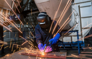 Industrial worker is welding automotive part in car factory