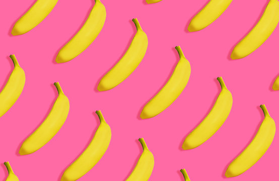 Yellow bananas pattern on vivid pink background, top view. Summer bright image, sweet tropical fruit concept, repetitive minimalist objects.