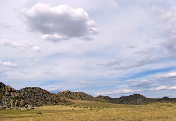 Wide steppe with yellow grass under a blue sky with white clouds Sayan mountains Siberia Russia