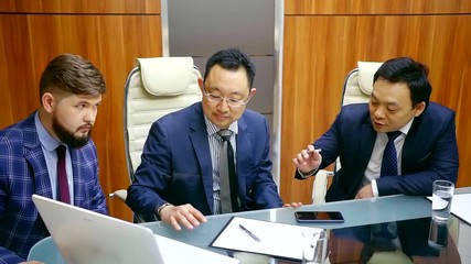 three asian music producers men are beating rhythm by fingers over table, they are wearing business suits