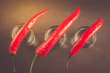 three shots of vodka and red pepper/three shots of vodka and red pepper on a dark stone background. Top view. Toned