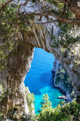 Capri, Italy. Capri Island in a beautiful summer day, with faraglioni rocks and natural stone arch. Close up of the natural rocky arc.