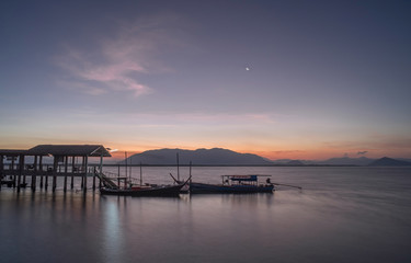 Early morning when the sun rises. With a boat waiting for passengers across the island. subject is blurred and noise.