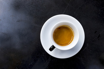 Obraz na płótnie Canvas espresso coffee with foam in white cup on black table