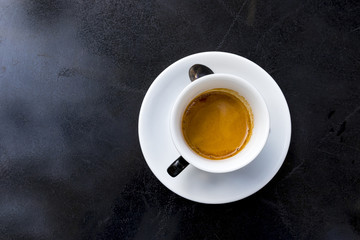 espresso coffee with foam in white cup on black table