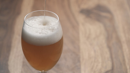 closeup pour apple cider in a wine glass on wood table