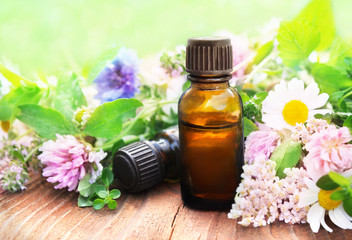 Essential oil bottles on medicinal flowers and herbs background, selective focus, toned