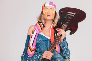 seductive woman with yellow sunglasses holds electric guitar