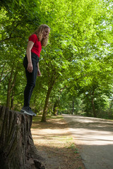 Girl about to jump from the trunk of a tree.