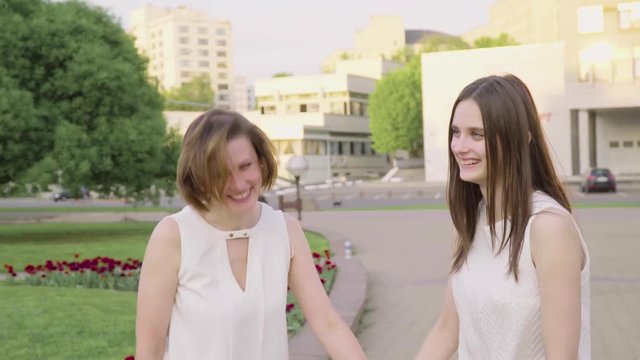 Mother and adult daughter laughing and chatting in the park on a sunny day. Attractive Brunette is Hugging Her Mom with Love and Tenderness